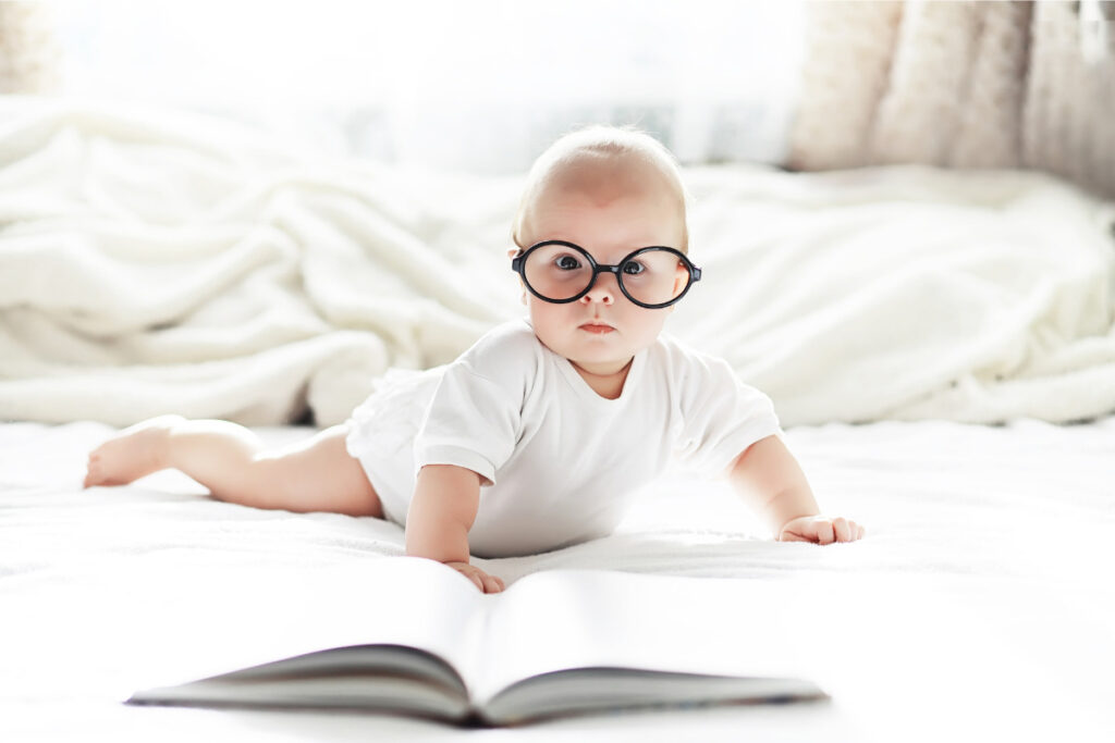 Bébé avec des lunettes devant un livre ouvert