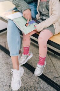 Un adulte et un enfant lisent un livre pour enfant en alphabet latin et en braille.