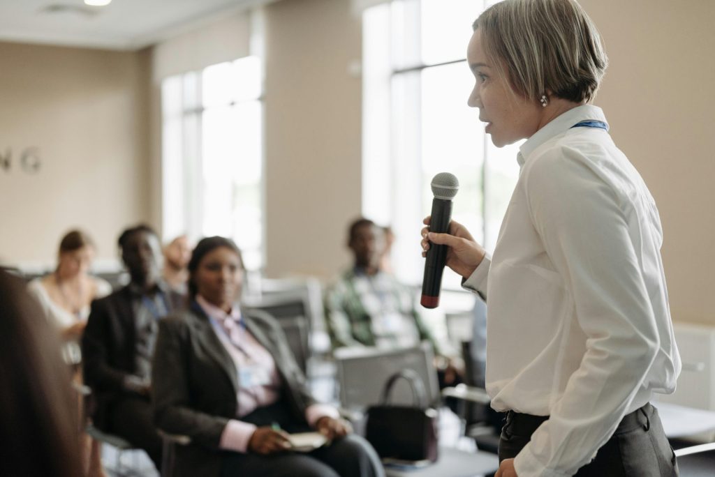 un femme parle au micro à un groupe de personne